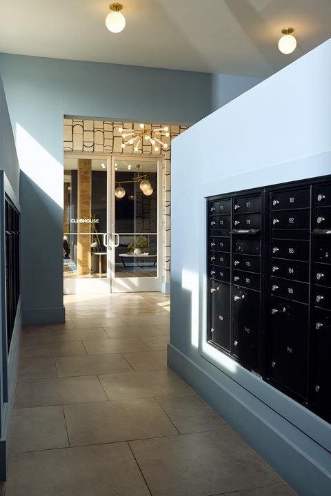 A hallway with a row of mailboxes on the right side.